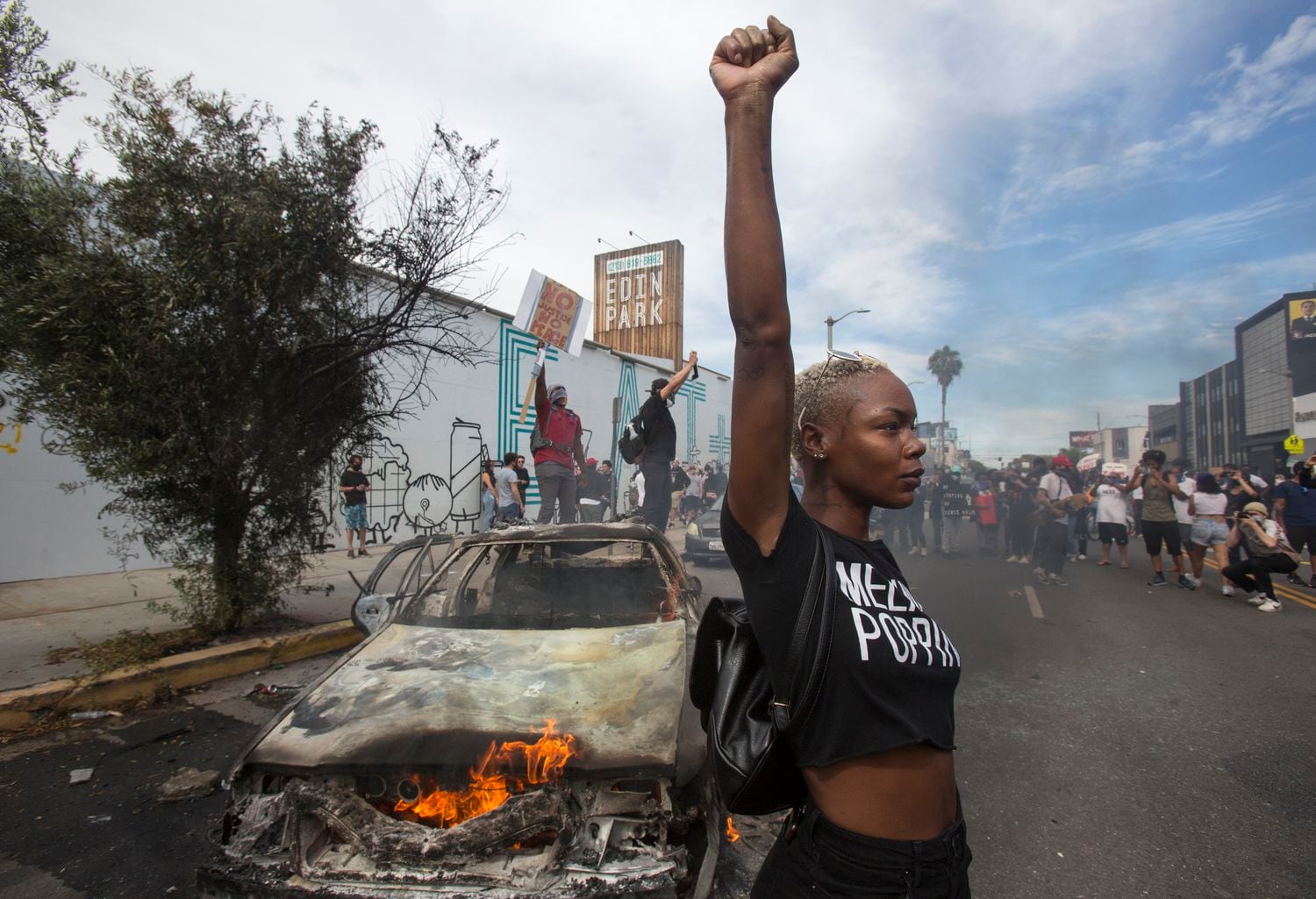 Una mujer posa delante de un coche de policía incendiado, el pasado sábado durante una protesta en Los Ángeles.