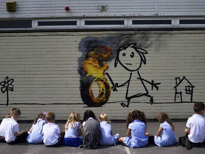 Alumnos de la escuela de primaria Bridge Farm, en Bristol, contemplan el dibujo de Banksy.