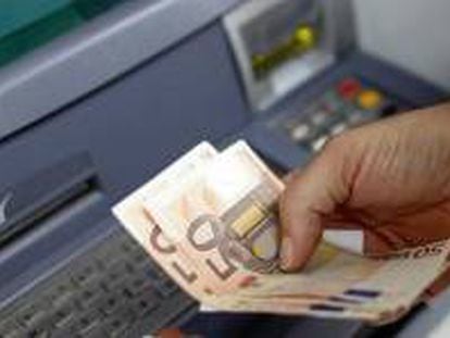 Un cliente de banca saca dinero de un cajero automático.