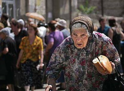 Una mujer georgiana lleva en su mano dos trozos de pan conseguidos en un reparto organizado por los rusos en Gori.