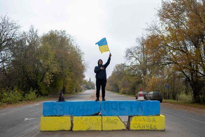 Um morador de Kherson agita a bandeira ucraniana em um posto de controle russo na entrada da cidade, após a retirada das tropas de Moscou. 
