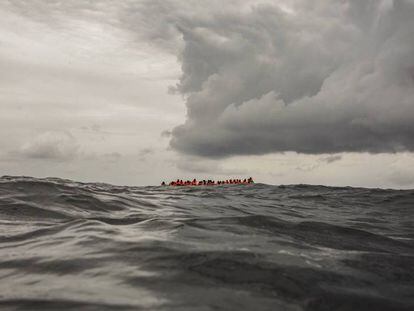 Migrantes a bordo de un bote que partió de Libia aguardan su rescate en el Mediterráneo Central. 