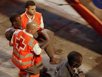 Miembros de Cruz Roja atienden a uno de los inmigrantes  llegados al puerto de Los Cristianos.