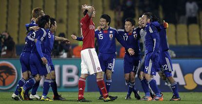 El danés Daniel Agger se lleva las manos a la cabeza al tiempo que los jugadores japoneses celebran su paso a la siguiente fase.