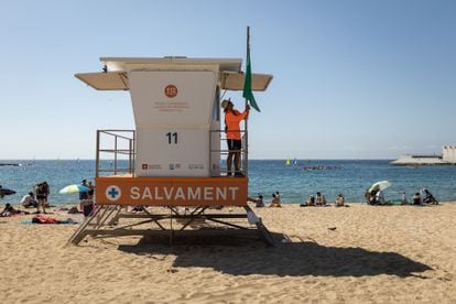 Un socorrista levanta la bandera verde en una de las torretas de vigilancia de la playa de Nova Icària de Barcelona