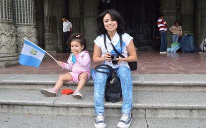 Una niña de dos años, acompañado por su madre, agita una bandera frente al antiguo palacio de gobierno de Guatemala.