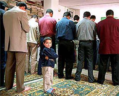 Un niño reza junto a su padre en el oratorio de la avenida de la Meridiana de Barcelona.