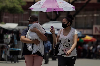 Dos mujeres se protegen de los rayos del sol con una sombrilla, en el centro de la Ciudad de México.