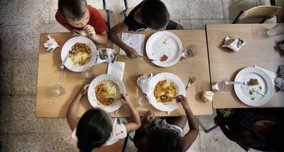 Un grupo de ni&ntilde;os come en un centro escolar de Sevilla abierto durante el verano dentro del programa del decreto de exclusi&oacute;n.