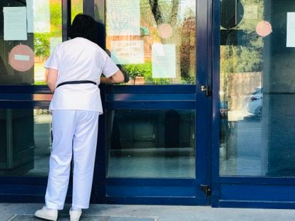 Una empleada del registro civil limpia los cristales de la puerta de acceso, en Madrid.