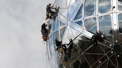 Trabajadores descienden por una de las nueve esferas del Atomium, estructura de 102 metros de altura construida para la Expo 58 en Bruselas, Bélgica.