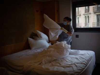 Una mujer hace la cama de un alojamiento en Cataluña.