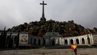 Una mujer con un paraguas con la bandera de España frente a la basílica del Valle de los Caídos.