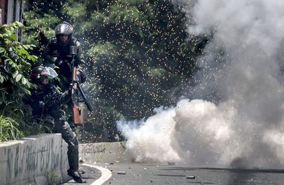 Dos miembros de la Guardia Nacional Bolivariana (GNB) se protegen durante los enfrentamientos con los opositores.