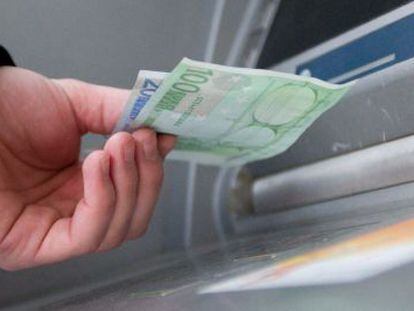 Un hombre saca euros de un cajero autom&aacute;tico. 