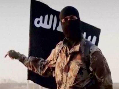 Un yihadista delante de la bandera del Estado Isl&aacute;mico (ISIS)
