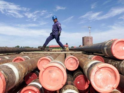 Un trabajador de Pemex cruza por encima de unos barriles de petróleo.