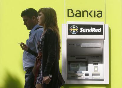 Dos personas pasan frente a un cajero de Bankia.