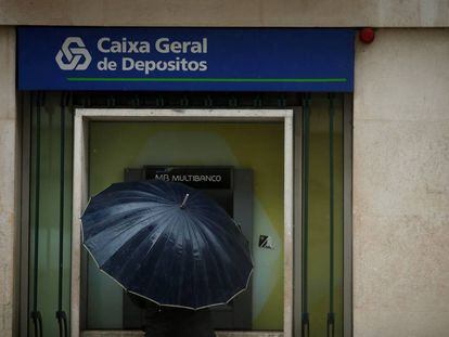 Un hombre saca dinero de un cajero de la Caixa Geral de Dep&oacute;sitos, en Lisboa.