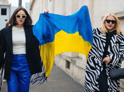 Dos asistentes a la semana de la moda de Milán sostienen la bandera de Ucrania a la salida del desfile de Prada.