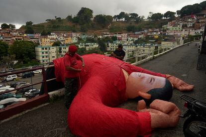 Partidarios del difunto presidente de Venezuela, Hugo Chávez, bajan un muñeco inflable de líder en el barrio 23 de Enero en Caracas, Venezuela, el jueves.