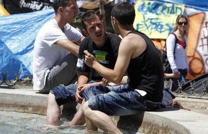 Dos jóvenes se refrescan en la fuente de la Puerta del Sol, en Madrid