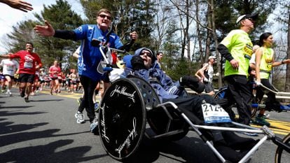Rick Hoyt, center, is pushed by his father Dick, left, along the Boston Marathon course, April 15, 2013, in Wellesley, Mass. Hoyt, who with his father pushing his wheelchair became a fixture at the Boston Marathon and other races for decades, has died. He was 61. Hoyt died of complications with his respiratory system, his family announced on Monday, May 22, 2023. (AP Photo/Michael Dwyer, File)