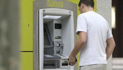 Un hombre saca dinero de un cajero automático de Bankia.