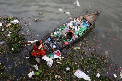 A woman collects plastic waste from the Buriganga River in Dhaka, Bangladesh, on September 16, 2020. 