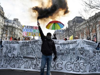 Un manifestante sostiene una bomba de humo frente a una pancarta anticapitalista durante el segundo día de huelga nacional contra la reforma de pensiones propuesta por el gobierno, en París el 31 de enero.