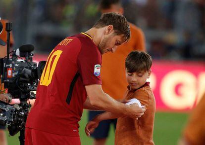 Totti cede su faja de capitán a un niño de los juveniles de la Roma tras su discurso de despedida.