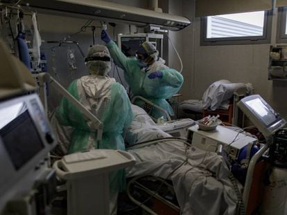 Personal sanitario totalmente protegido atiende a un paciente ingresado en la Unidad de Cuidados Intensivos del Hospital Infanta Sofía en San Sebastián de los Reyes (Madrid).