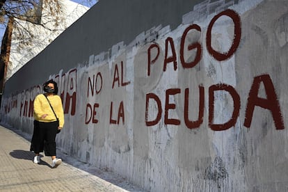 Una mujer pasa frente a una pintada contra el pago de la deuda, en Buenos Aires.