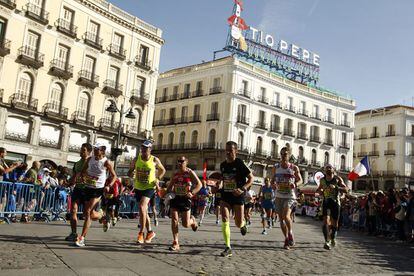 Varios corredores de la Maratón Popular de Madrid, pasan por delante de la nueva ubicación del cartel del "Tío Pepe" en la Plaza de Sol, de Madrid.