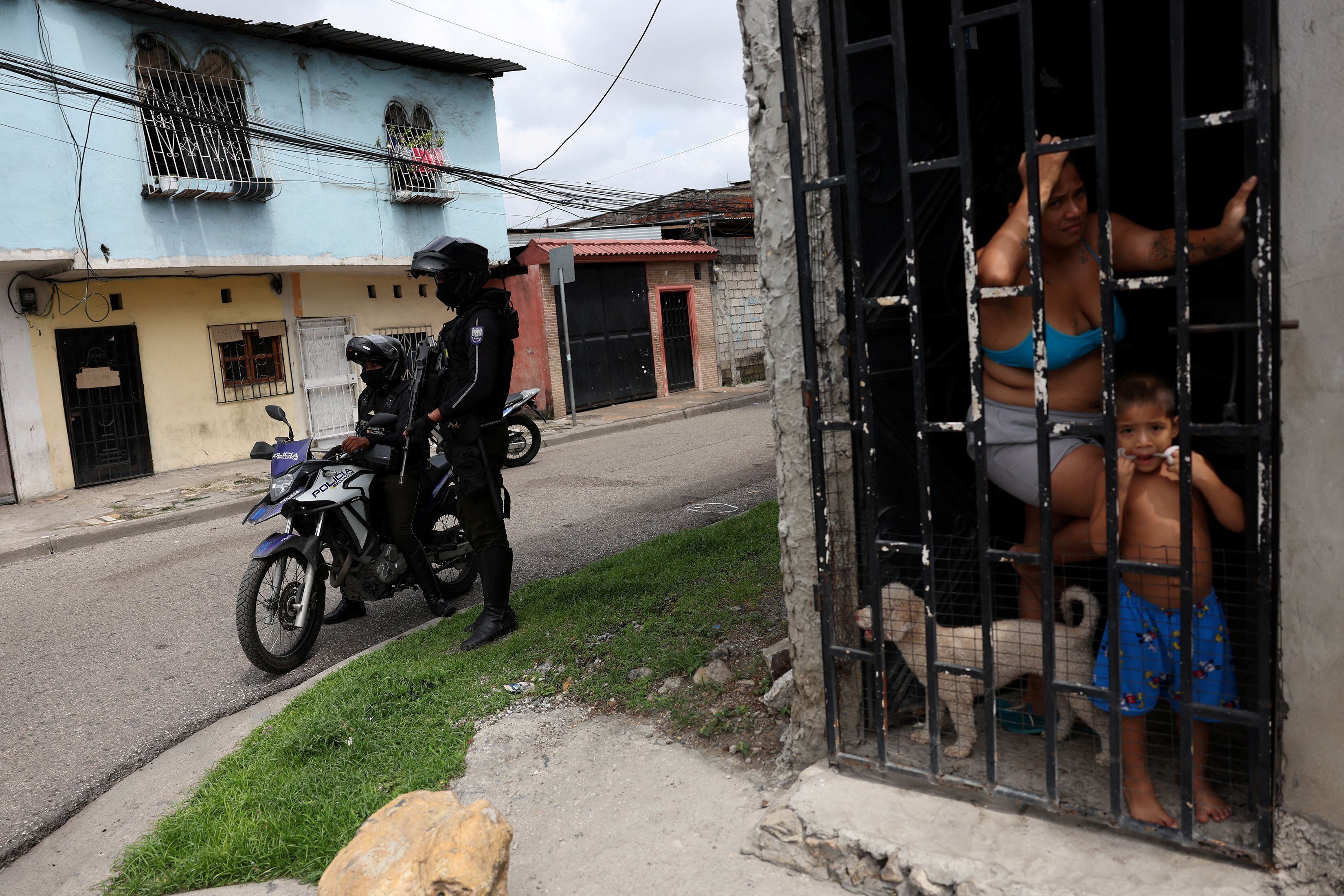 Habitantes de Guayaquil asoman a su puerta mientras policías preparan un retén, este viernes en Guayaquil.