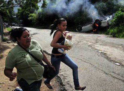 Seguidoras del depuesto presidente hondureño huyen de los incidentes registrados ayer en el cementerio de Tegucigalpa.