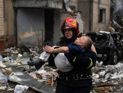 Un bombero carga a un hombre en una zona afectada por el impacto de un misil ruso, en Kyev (Ucrania), el pasado 2 de enero.