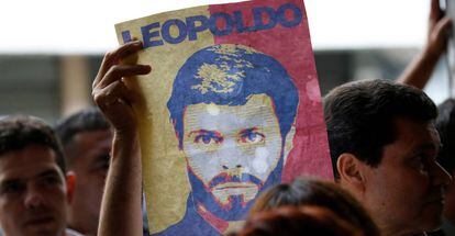 Un partidario de Leopoldo L&oacute;pez muestra un cartel con su rostro a las puertas de un tribunal de Caracas, el 20 de junio