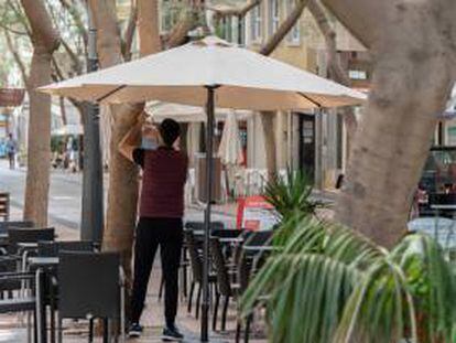 Un camarero coloca una sombrilla en la terraza de un bar en la calle Betenchourt Alfonso de Santa Cruz de Tenerife.