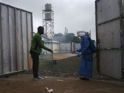 Un trabajador sanitario roc&iacute;a a un posible enfermo de &eacute;bola a la entrada de un centro de tratamiento de Monrovia (Liberia).