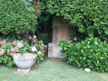 Una pila románica procedente de Muxía y uno de los diversos escudos originarios de pazos que Franco usó para decorar el jardín.
