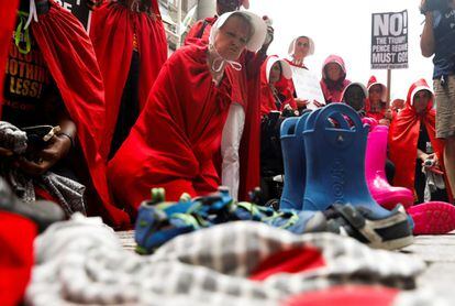 Activistas vestidas como mujeres destinadas a la reproducción de la serie 'The Handmaid's Tale' depositan zapatos y ropa de niños inmigrantes separados de sus padres, en Manhattan (Estados Unidos), el 31 de julio de 2018.