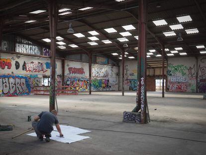 Un trabajador comprobando los planos de construcción en el lugar donde se creará un campamento habilitado para los refugiados, en París (Francia).