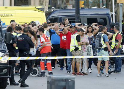 Un grupo de gente con los brazos en alto ante el despliegue policial en las Ramblas de Barcelona.