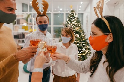 Un grupo de personas con mascarilla durante un brindis por Navidad. GETTY IMAGES