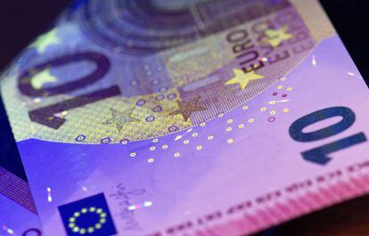 Una l&aacute;mpara de luz negra ilumina los distintivos de seguridad de los nuevos billetes de 10 euros, durante su presentaci&oacute;n en el Bundesbank.