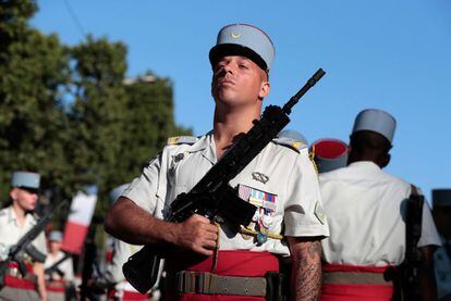 Un soldado francés sostiene su rifle mientras se reúne con sus copañeros para el inicio del desfile militar anual del Día de la Bastilla.