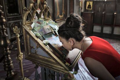 La celebración empieza en el monasterio Bistrita con un misa que tiene como finalidad borrar los pecados de los fieles. En la imagen, una joven besa un ícono religioso ortodoxo, rodeado de dinero, en Costesti (Rumanía).