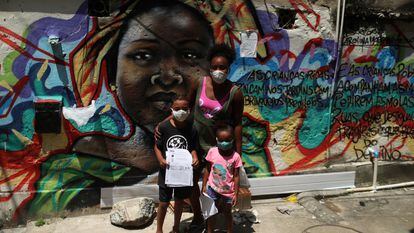 Janice Delfim, fundadora de una iniciativa para facilitar el acceso a la educación de los niños perjudicados por el cierre de escuelas por la covid-19, posa con dos de las beneficiarias de su proyecto, en la favela Prazeres de Río de Janeiro, en Brasil.