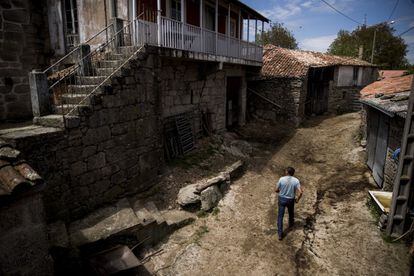 José Enrique González camina por las calles de la aldea de A Teixeira donde vive de una pequeña explotación ganadera. Varias de las viviendas del pueblo están vacías y abandonadas.